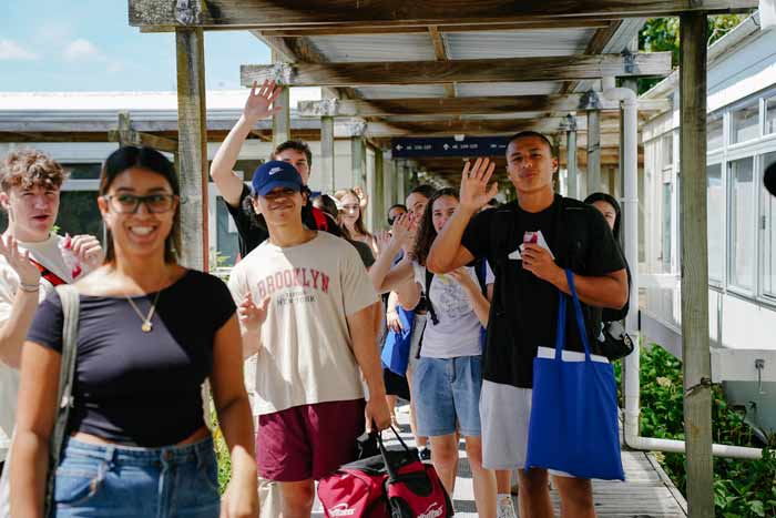 Students at AUT smiling and waving towards the camera