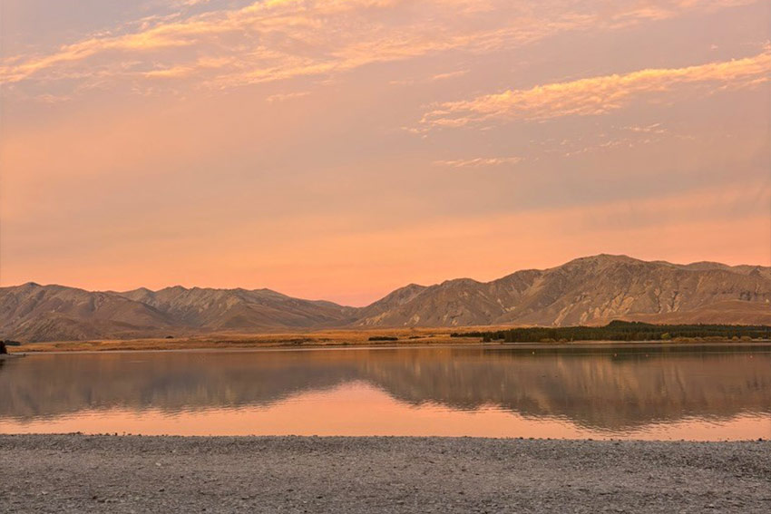 A wide shot of mountains in the afternoon, the sky is pink