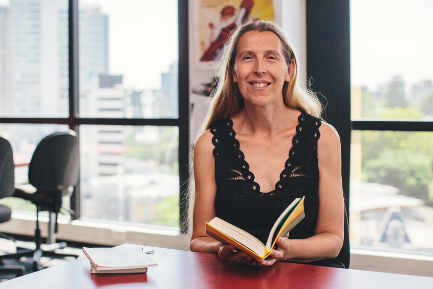 Siobhan Harvey holding a book of poetry in her office.