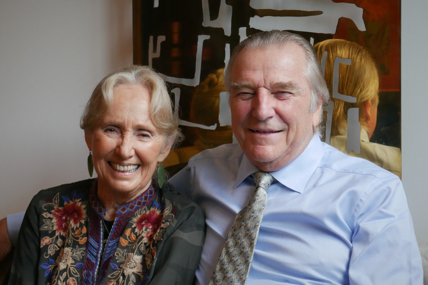 Dr Lola Van Wagenen and Dr George Burrill sitting on a couch, smiling.