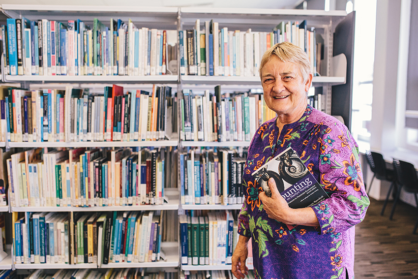 Marilyn Waring standing in a library.