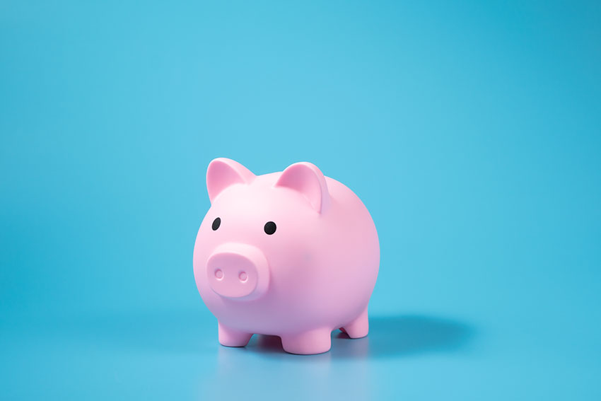 A pink piggy bank on blue background with copy space.