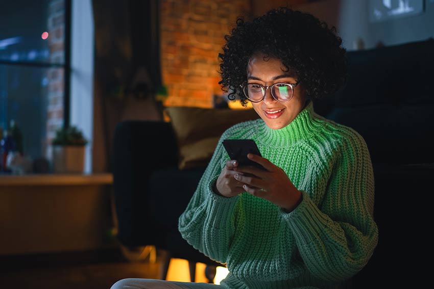 Woman Typing Message on her Smartphone in the Evening at Home.