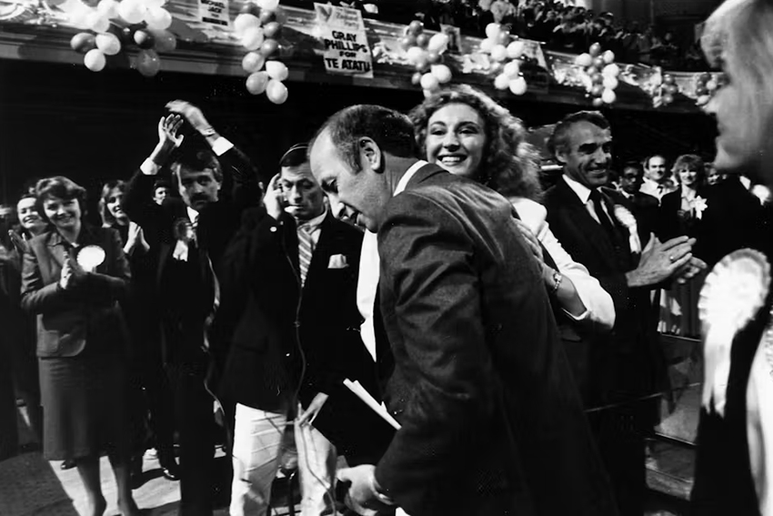 Bob Jones in a hall with people clapping and smiling, and balloons. Everyone is dressed in formal attire.