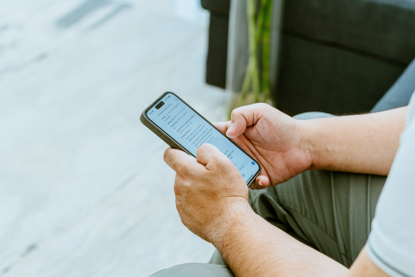 A photo showing only a man's forearms and hands using a smartphone on a couch.