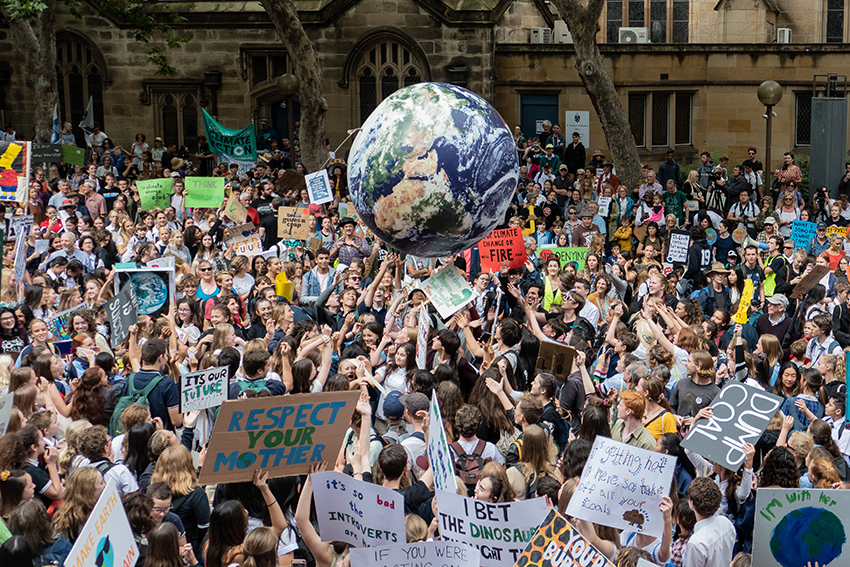 A climate protest march with protesters hold up a giant globe.