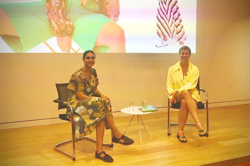 Nancy Johnson-Hunt and Emily Miller-Sharma sitting on stage smailing at the camera.