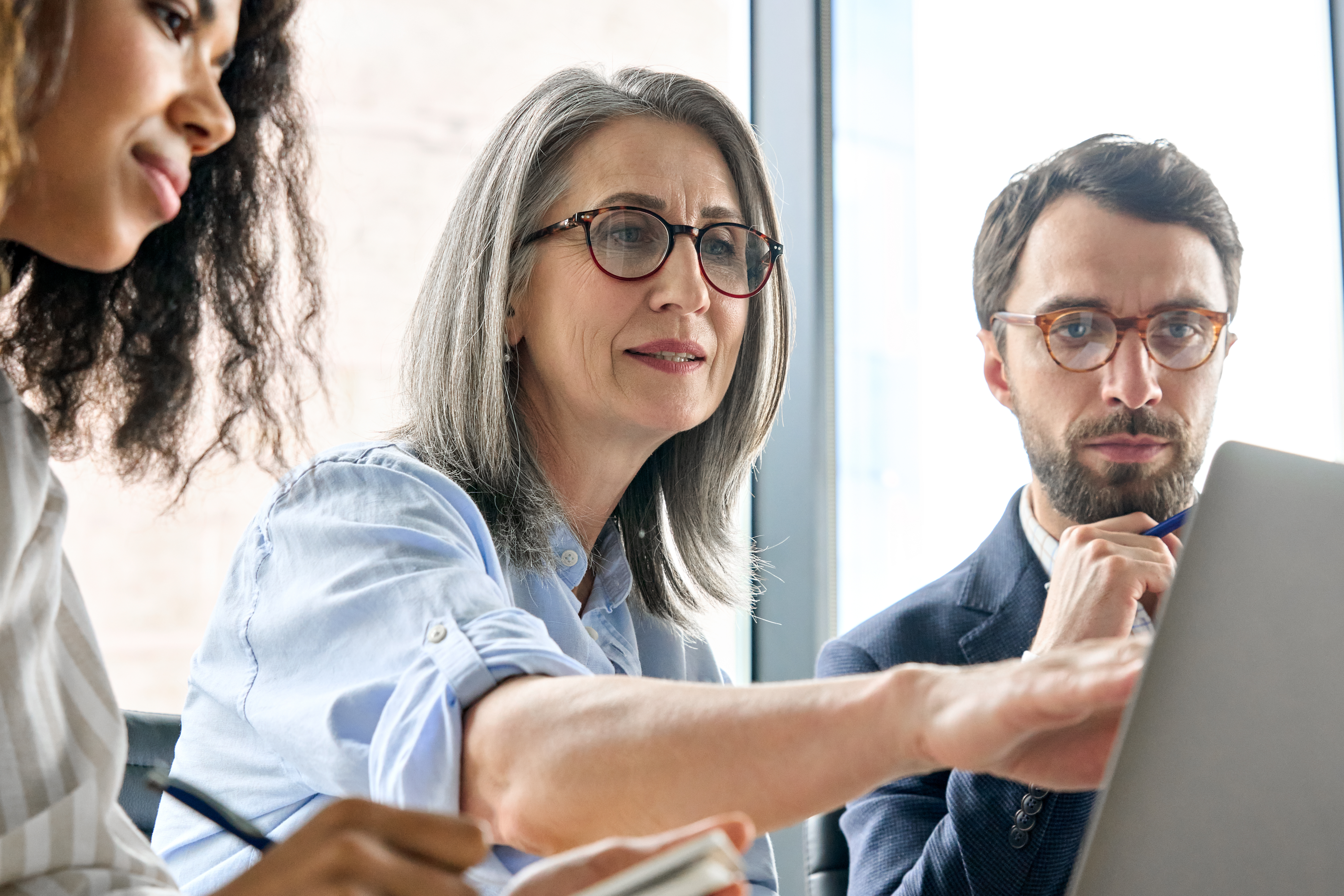 An older woman working with two younger colleagues.