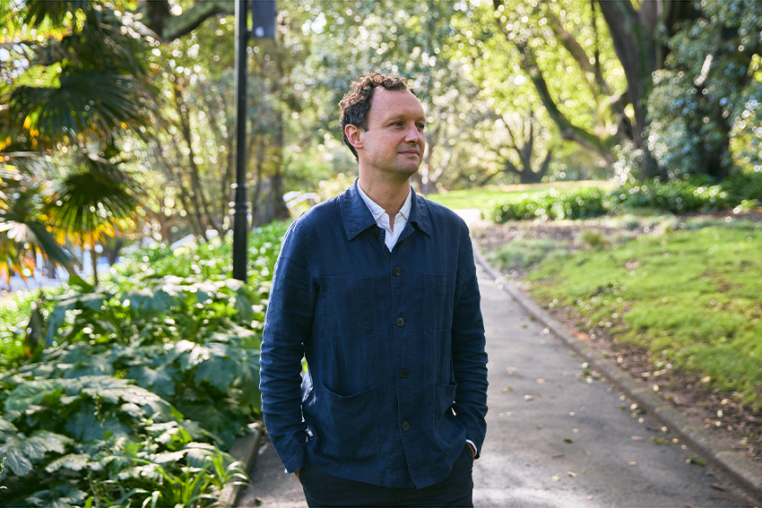 David Hall standing hands in pockets amongst the trees in Albert Park.