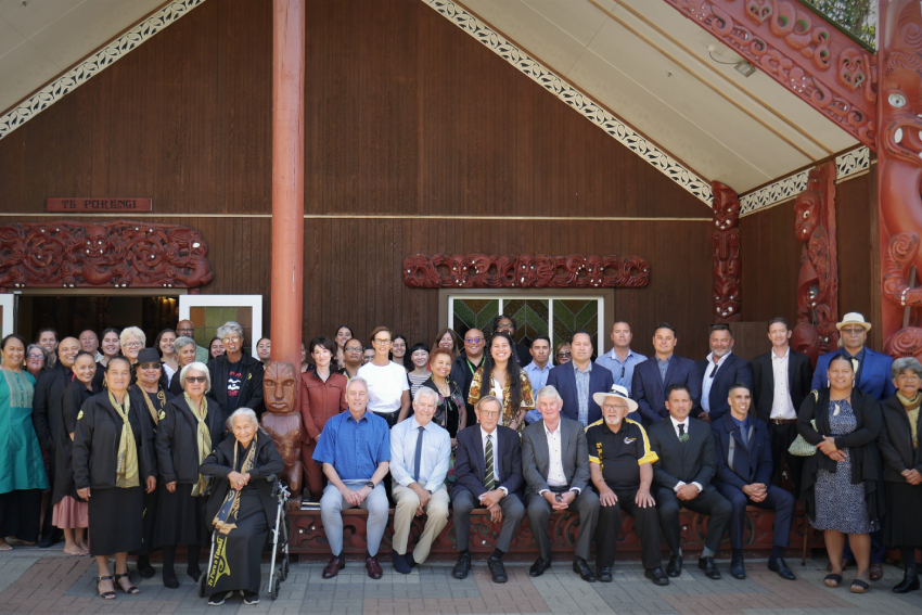 About 50 people lined up for a photo in front of the wharenui.