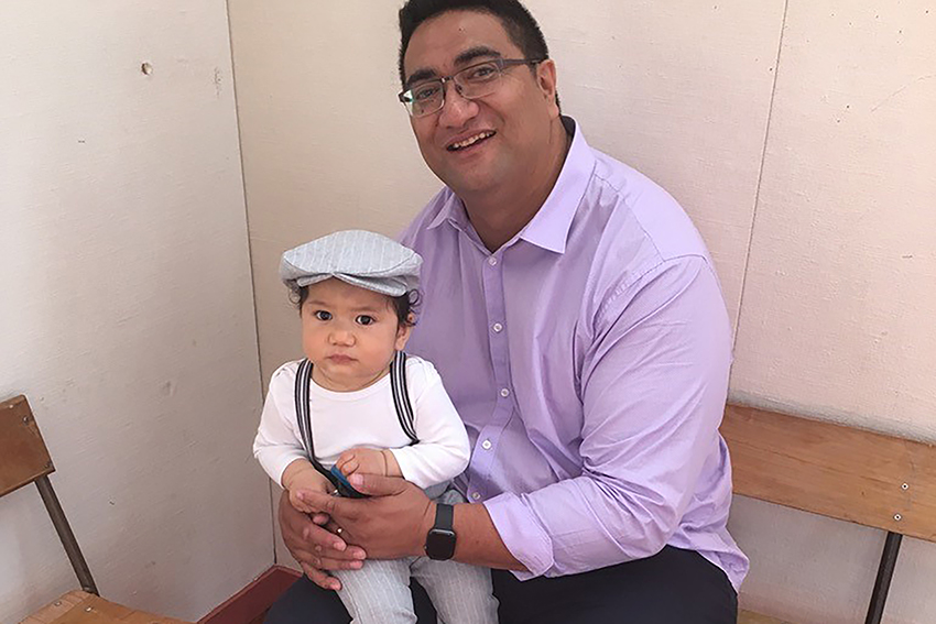 Associate Professor El-Shadan Tautolo with his child on his knee.