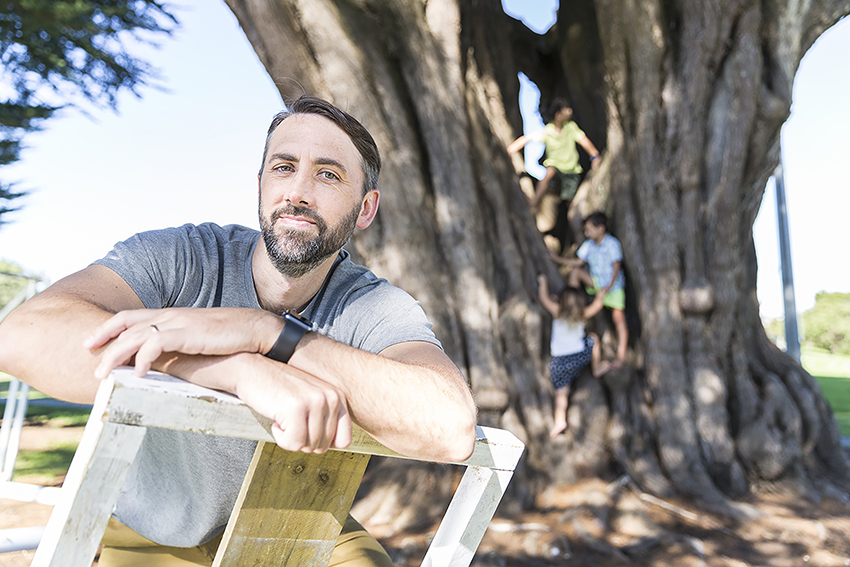 Professor Scott Duncan with children playing in a tree behind.