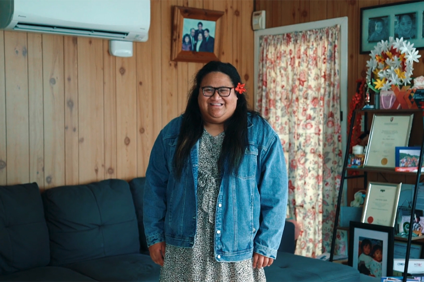 Nu’uali’i standing in her living room, smiling.