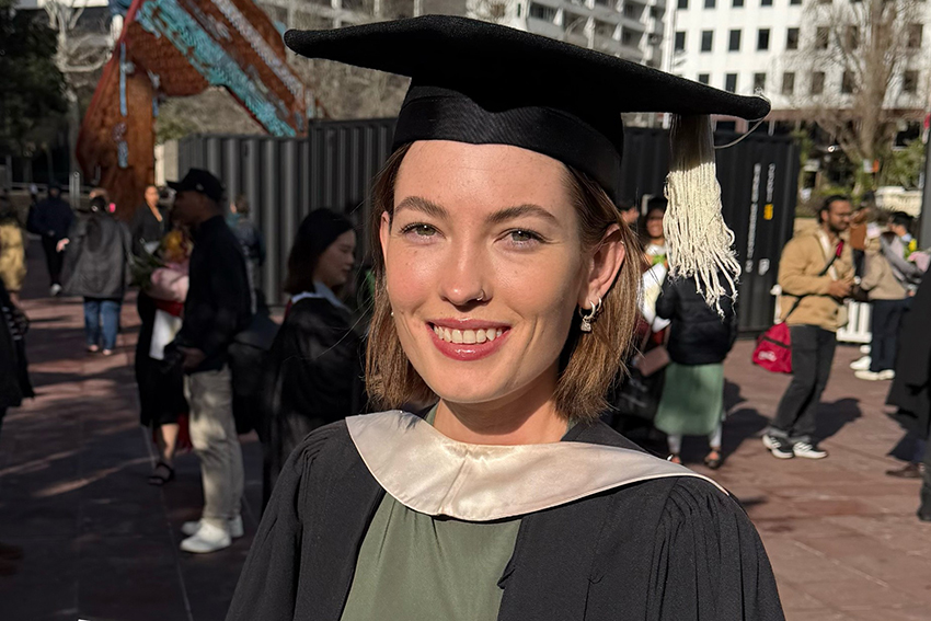 A young woman wearing academic regalia, smiling on her graduation day.