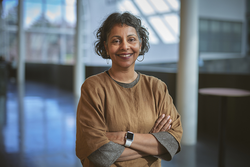 Professor Rhema Vaithianathan standing smiling with arms crossed.