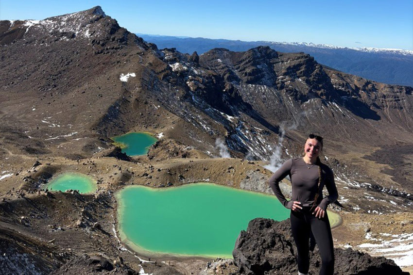 Sydney posing on a mountain, in the background is a natural water reserve that is smoking