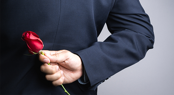 A rose held behind the back of a gentleman