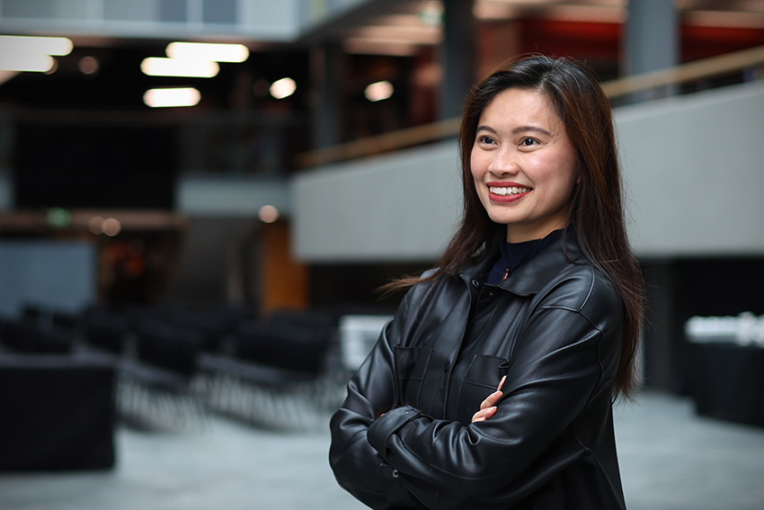 AUT Senior Lecturer Sandra Goh standing arms folded and smiling.