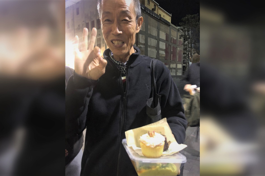 A customer of Sunday Blessings, smiling and holding food.