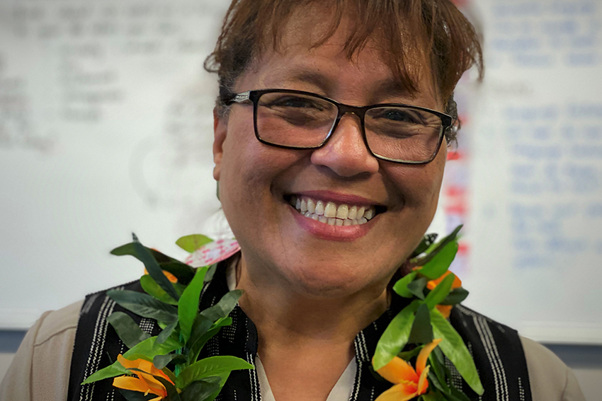 Rosa Kalauni smiling in front of a classroom whiteboard.